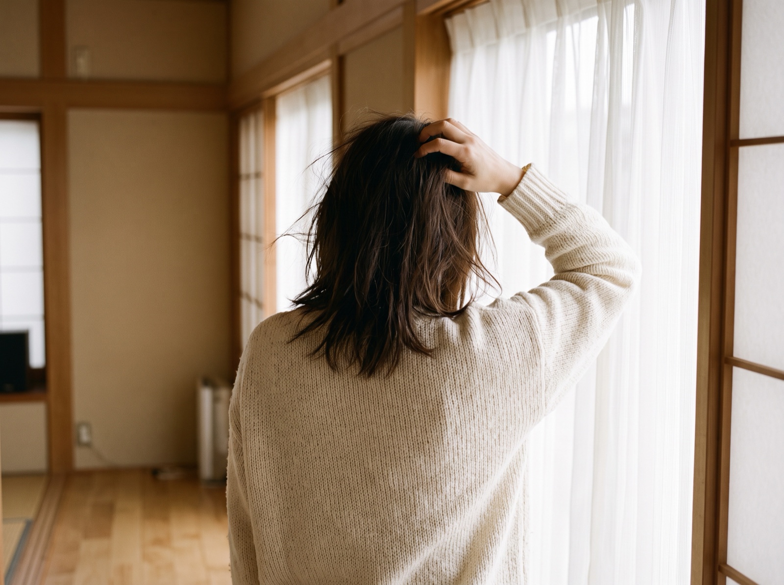 朝の窓辺で髪を整える後ろ姿
