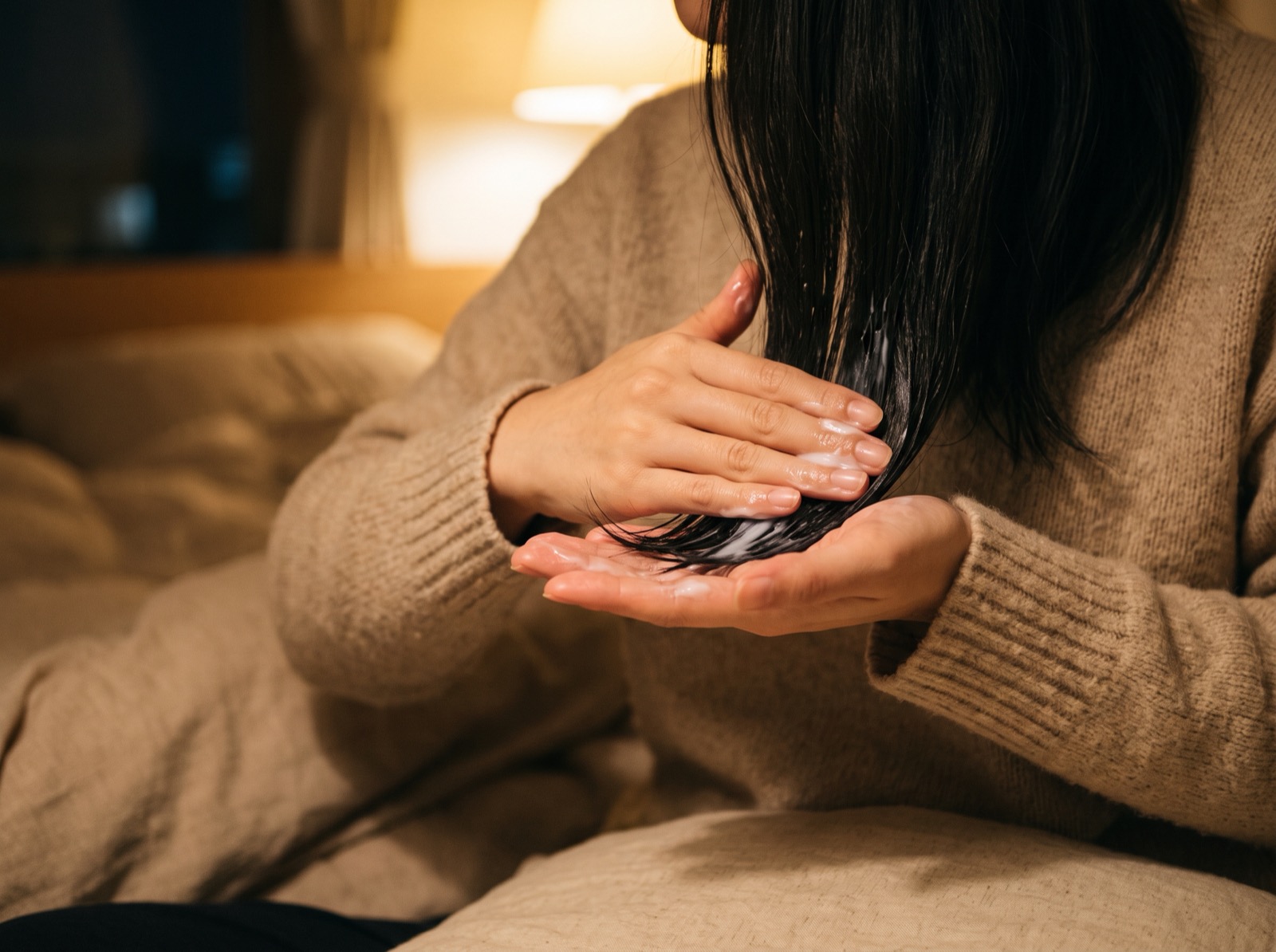 毛先にトリートメントをなじませる手元
