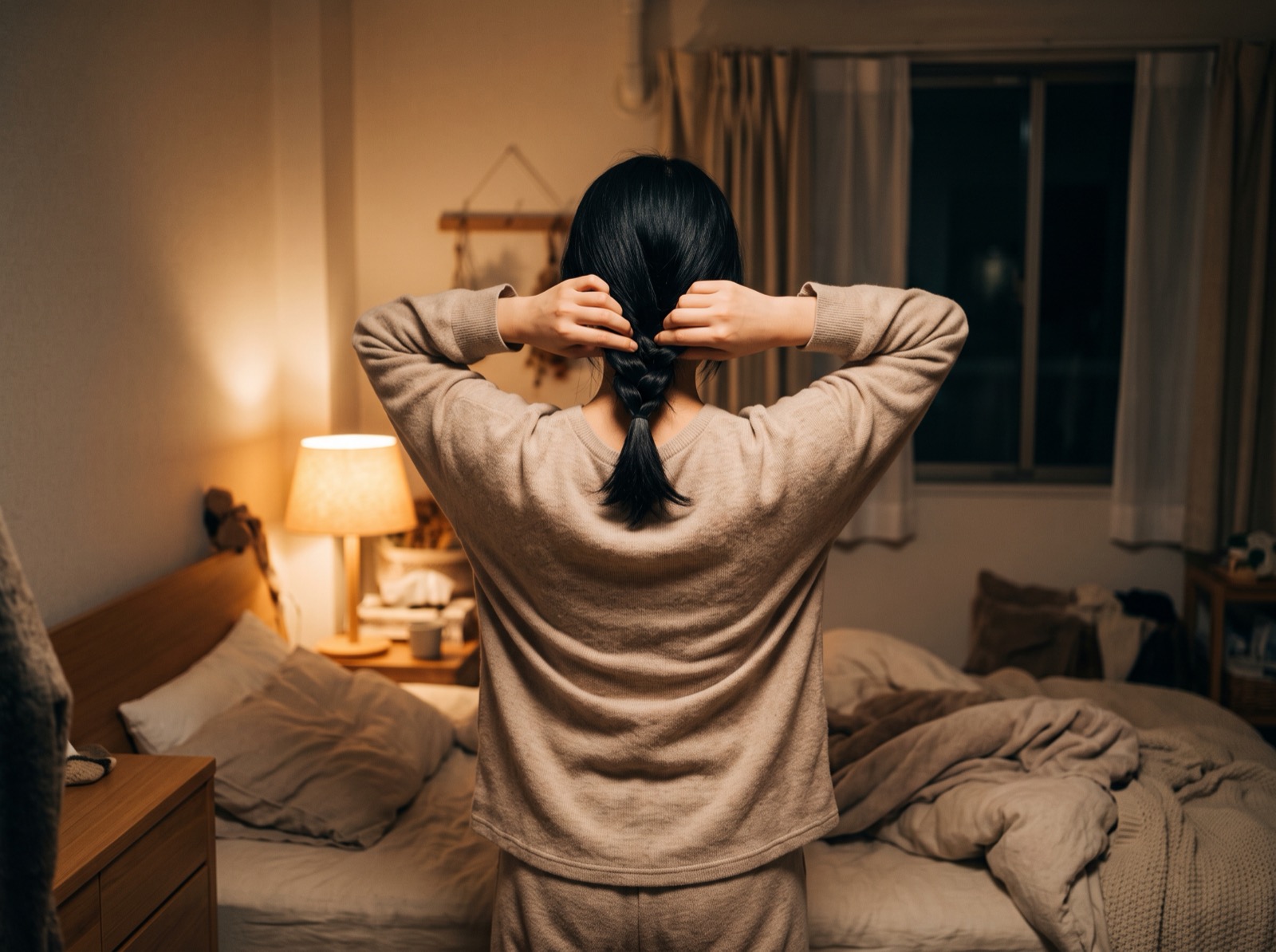寝る前に髪をゆるくまとめる女性の後ろ姿