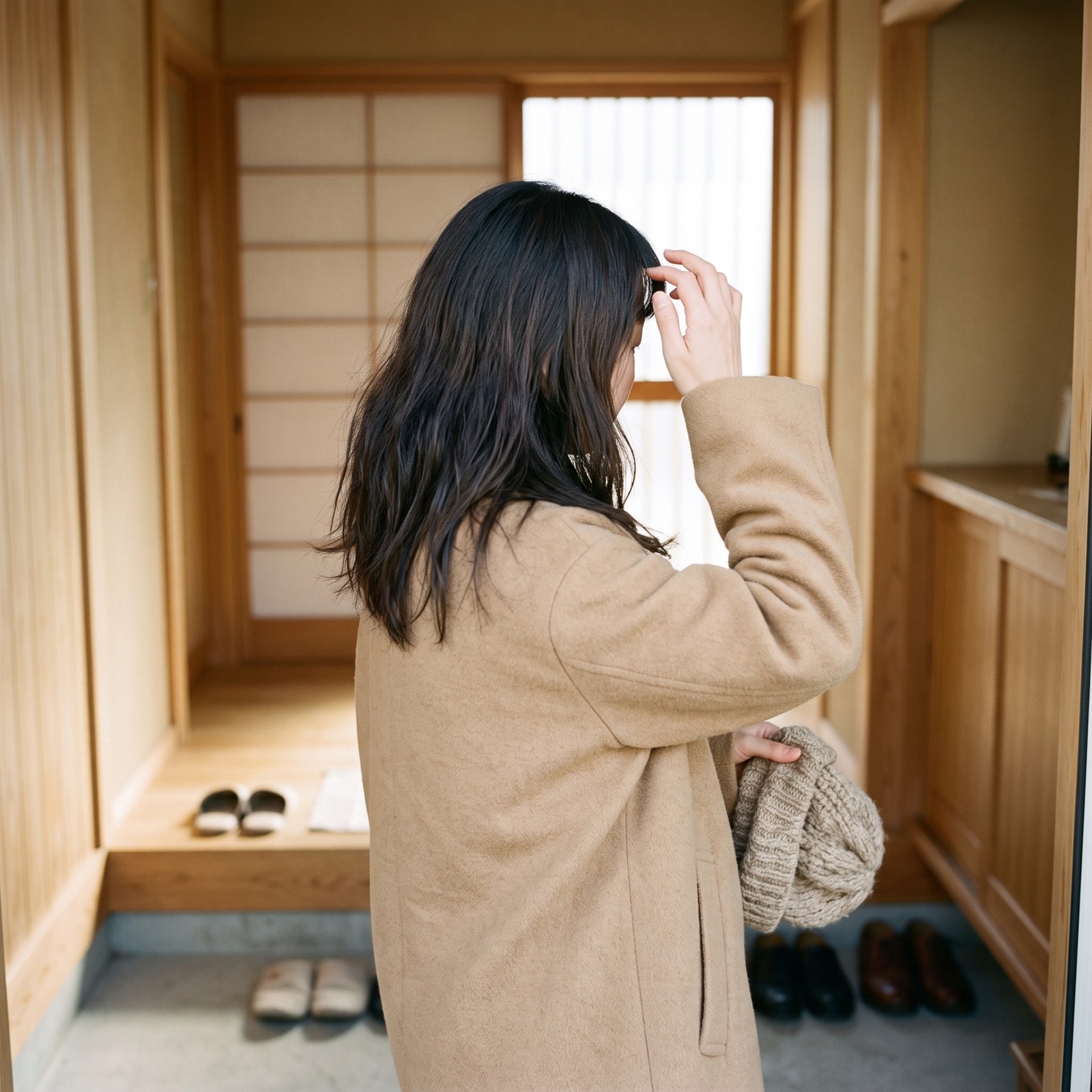 ニット帽を手に前髪の生えぎわに手をそえる後ろ姿
